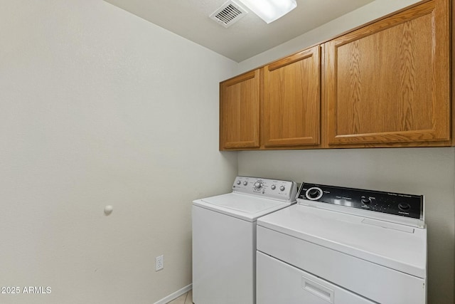 clothes washing area featuring visible vents, washing machine and clothes dryer, cabinet space, and baseboards