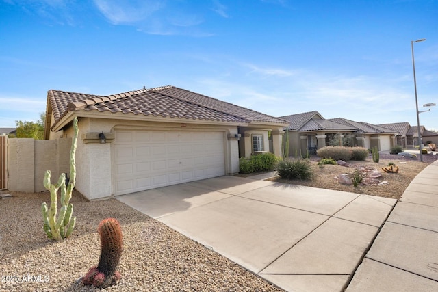 view of front of house featuring driveway, a tiled roof, an attached garage, fence, and stucco siding