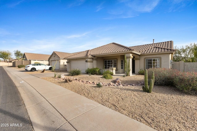 mediterranean / spanish-style home featuring a garage, fence, a tile roof, concrete driveway, and stucco siding