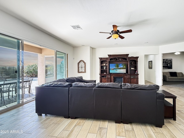 living room with wood tiled floor, visible vents, and a ceiling fan