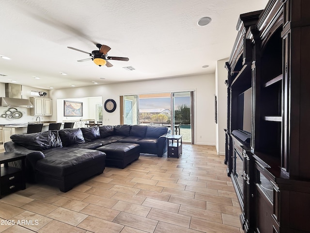 living room with baseboards, visible vents, a ceiling fan, a textured ceiling, and recessed lighting