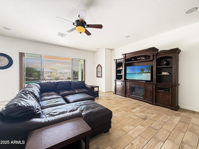 living room featuring visible vents, baseboards, ceiling fan, a textured ceiling, and light wood-style floors