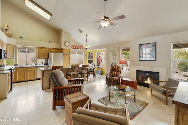 tiled living room featuring ceiling fan, high vaulted ceiling, sink, and a fireplace