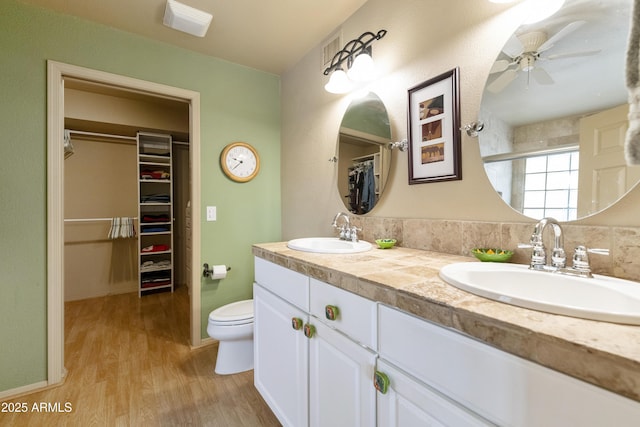 bathroom featuring a shower with door, ceiling fan, vanity, wood-type flooring, and toilet