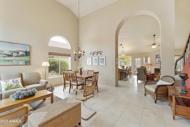 living room with ceiling fan with notable chandelier, light tile patterned flooring, and high vaulted ceiling