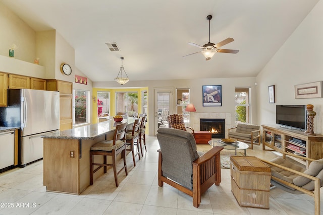 living room with ceiling fan, high vaulted ceiling, light tile patterned floors, and a fireplace