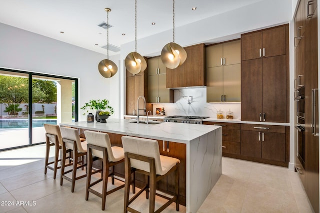 kitchen featuring backsplash, a spacious island, sink, decorative light fixtures, and a kitchen bar