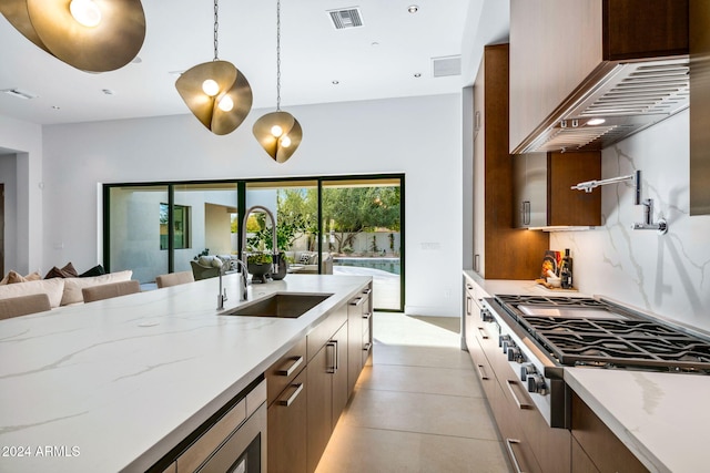 kitchen featuring light stone countertops, appliances with stainless steel finishes, backsplash, sink, and hanging light fixtures