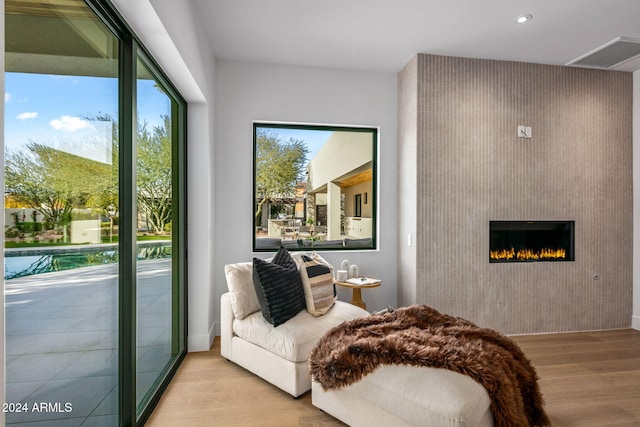 living area with light wood-type flooring, a large fireplace, and a wealth of natural light