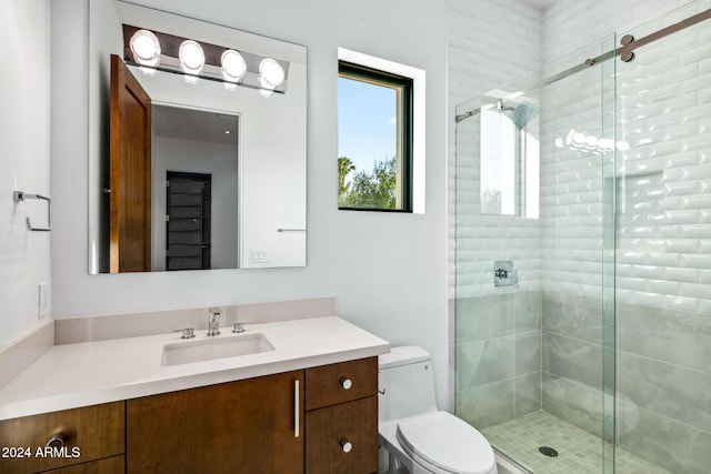 bathroom featuring a shower with door, vanity, and toilet