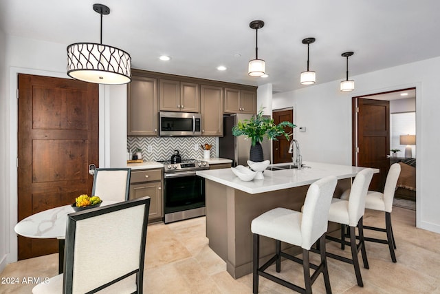 kitchen with a center island with sink, decorative light fixtures, sink, and appliances with stainless steel finishes