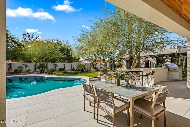 view of swimming pool featuring exterior kitchen, a patio, and grilling area