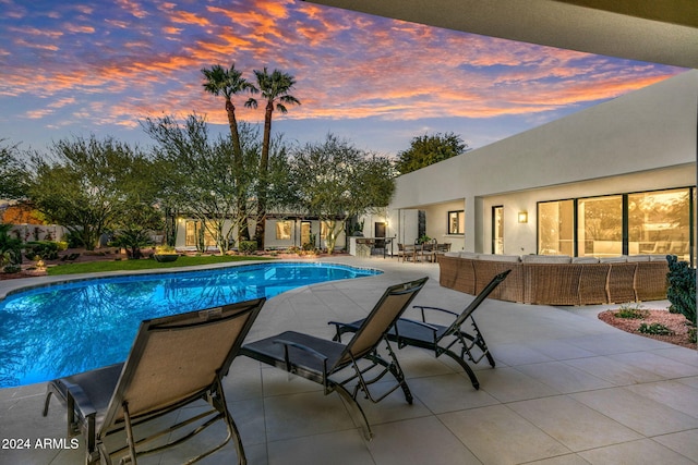 pool at dusk with an outdoor living space and a patio