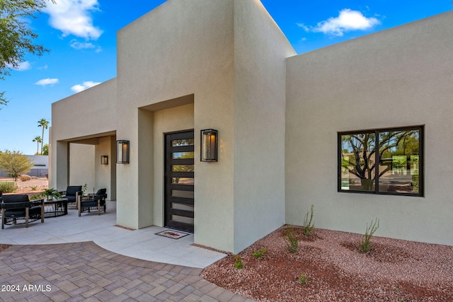 view of exterior entry with an outdoor living space and a patio