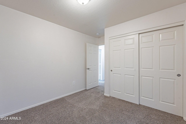 unfurnished bedroom featuring a closet, carpet, and a textured ceiling