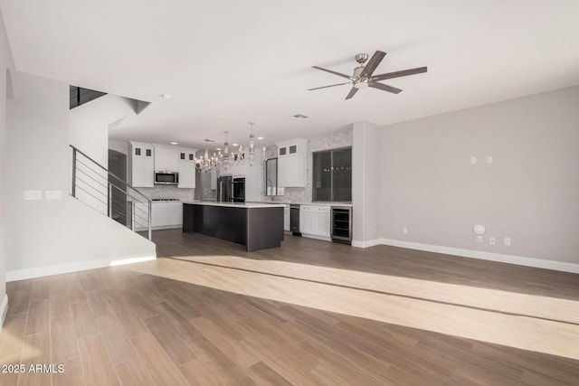 unfurnished living room with wood-type flooring, beverage cooler, and ceiling fan