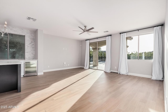 unfurnished living room featuring ceiling fan, beverage cooler, and wood-type flooring