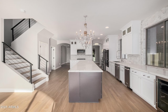 kitchen featuring white cabinets, hanging light fixtures, wine cooler, a kitchen island, and stainless steel appliances