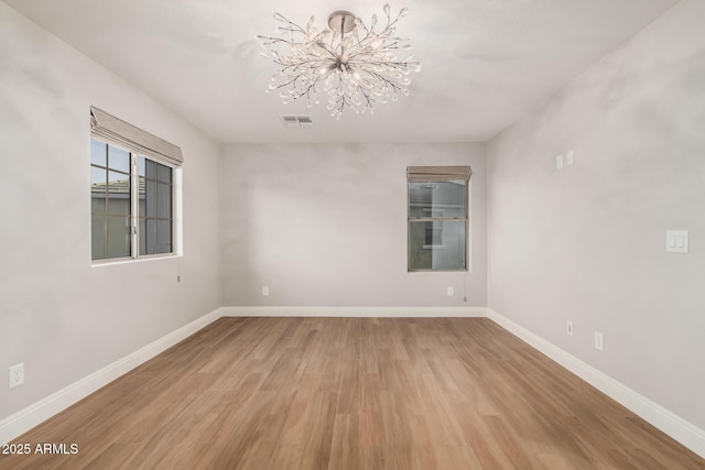 spare room featuring hardwood / wood-style flooring and a notable chandelier