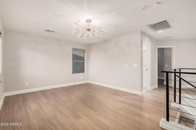 empty room with light hardwood / wood-style floors and an inviting chandelier