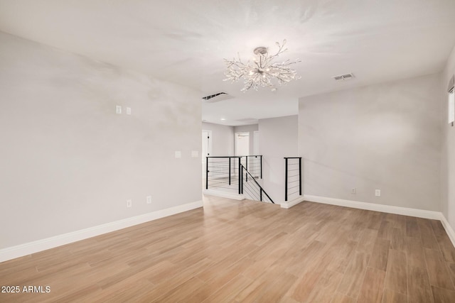 unfurnished room with light wood-type flooring and an inviting chandelier