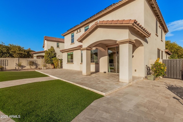 rear view of house featuring a lawn and a patio area