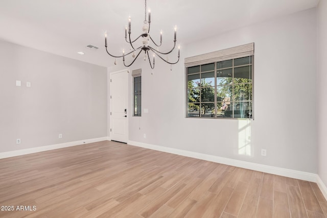 unfurnished room featuring light hardwood / wood-style floors and an inviting chandelier