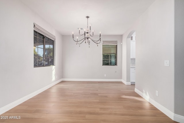 unfurnished dining area with light wood-type flooring and an inviting chandelier