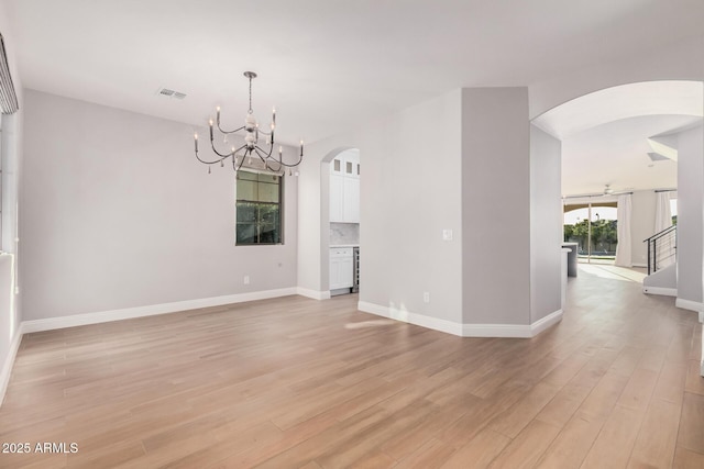 unfurnished room with a chandelier and light wood-type flooring