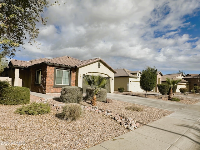 view of front of property featuring an attached garage, a tile roof, driveway, stone siding, and stucco siding