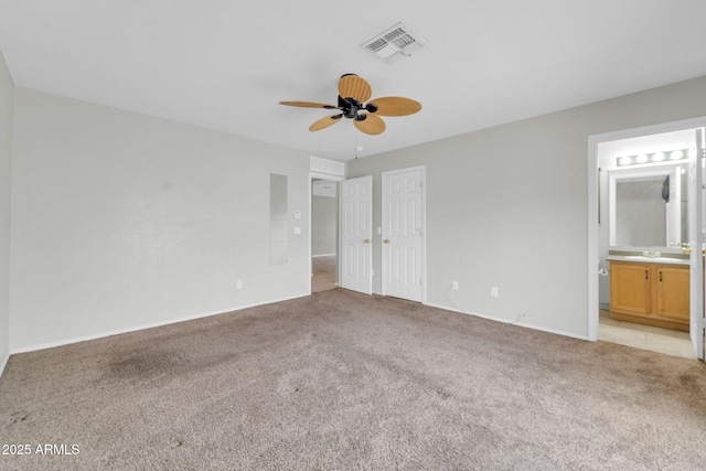 unfurnished bedroom featuring sink, a closet, ceiling fan, light carpet, and ensuite bathroom