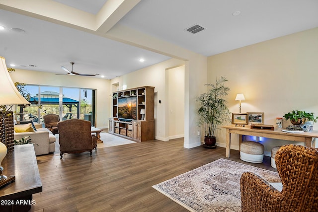 living room featuring beam ceiling, dark hardwood / wood-style floors, and ceiling fan