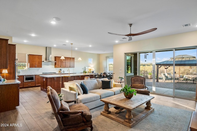 living room featuring ceiling fan, sink, and light hardwood / wood-style floors