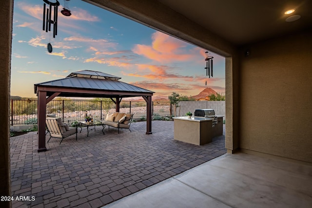 patio terrace at dusk with a gazebo, grilling area, area for grilling, and an outdoor hangout area