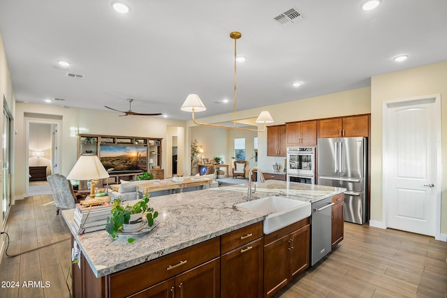 kitchen featuring pendant lighting, a kitchen island with sink, sink, ceiling fan, and stainless steel appliances