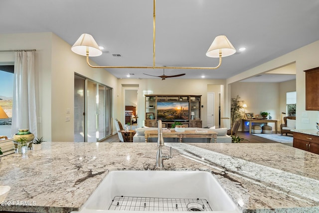 kitchen with light stone countertops, hanging light fixtures, and a healthy amount of sunlight