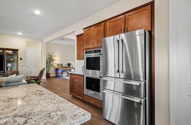 kitchen featuring light stone countertops, stainless steel appliances, and dark wood-type flooring