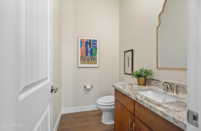 bathroom with wood-type flooring, vanity, and toilet