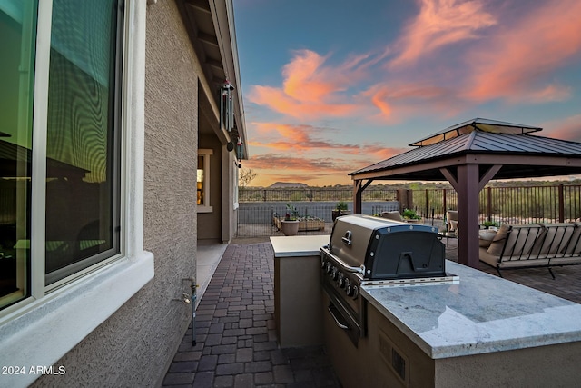 patio terrace at dusk with a gazebo, grilling area, and area for grilling