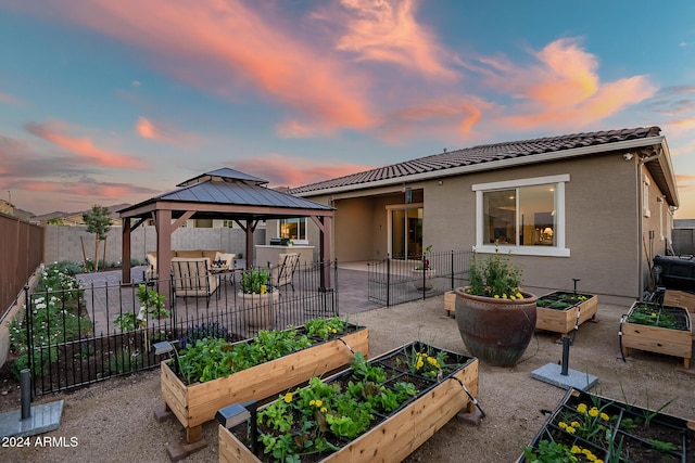 back house at dusk with a gazebo