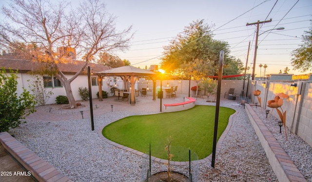 yard at dusk featuring a gazebo and a patio