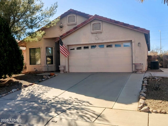 view of front of home with a tiled roof, central AC, stucco siding, a garage, and driveway