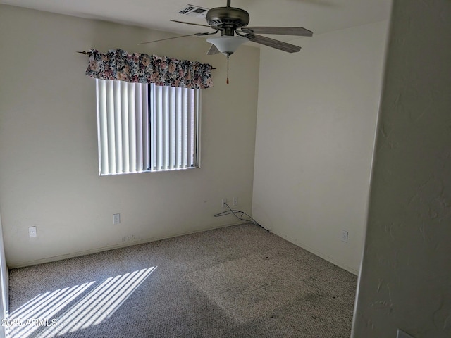 unfurnished room with visible vents, a ceiling fan, and carpet flooring