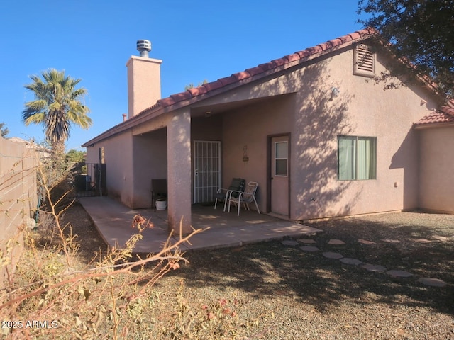 back of house featuring stucco siding, a patio, a tile roof, and fence