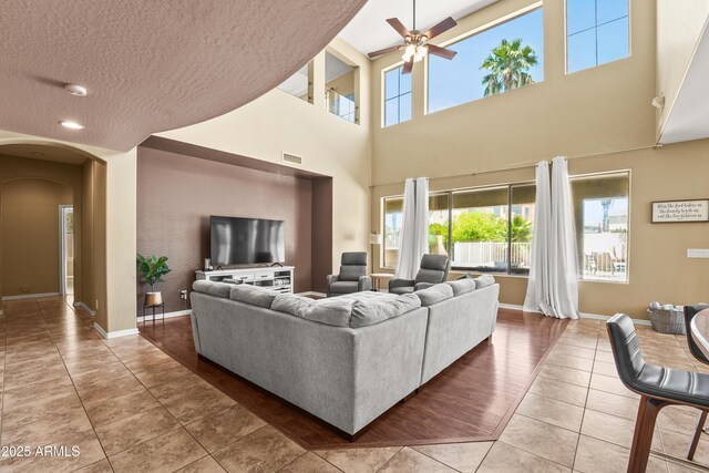 14430 W Windsor Ave, Goodyear, AZ 85395 - tiled living room featuring arched walkways, ceiling fan, plenty of natural light, a textured ceiling, and a towering ceiling