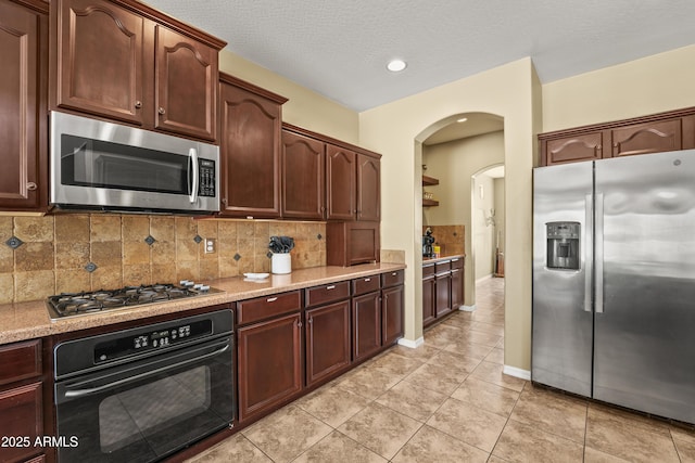 14430 W Windsor Ave, Goodyear, AZ 85395 - kitchen featuring appliances with stainless steel finishes, arched walkways, light tile patterned floors, tasteful backsplash, and a textured ceiling