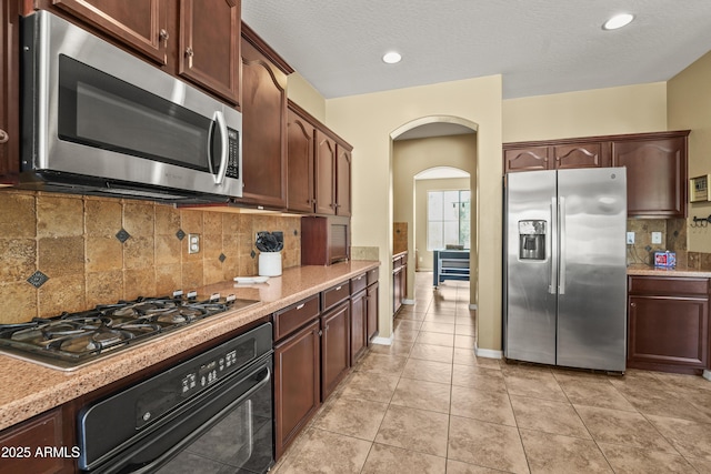 14430 W Windsor Ave, Goodyear, AZ 85395 - kitchen featuring stainless steel appliances, arched walkways, decorative backsplash, light tile patterned floors, and recessed lighting