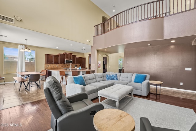 14430 W Windsor Ave, Goodyear, AZ 85395 - living area featuring light wood-style floors, baseboards, a towering ceiling, recessed lighting, and a chandelier