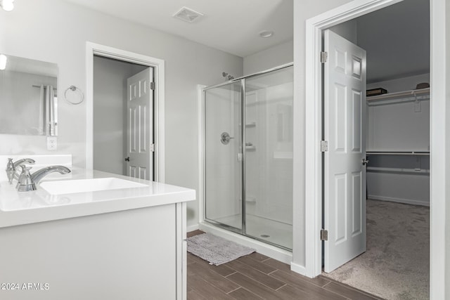 bathroom with wood-type flooring, vanity, and a shower with shower door