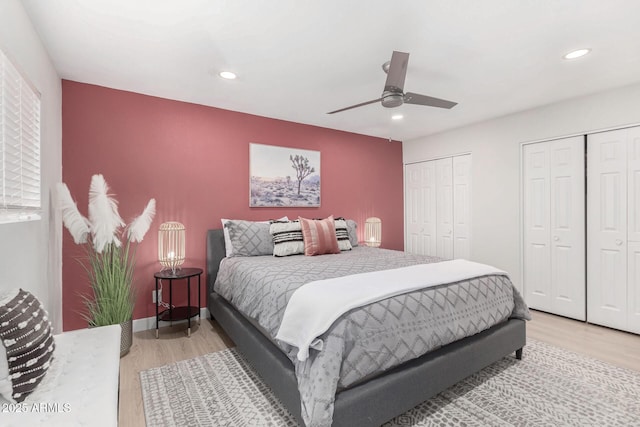 bedroom with ceiling fan, hardwood / wood-style flooring, and multiple closets